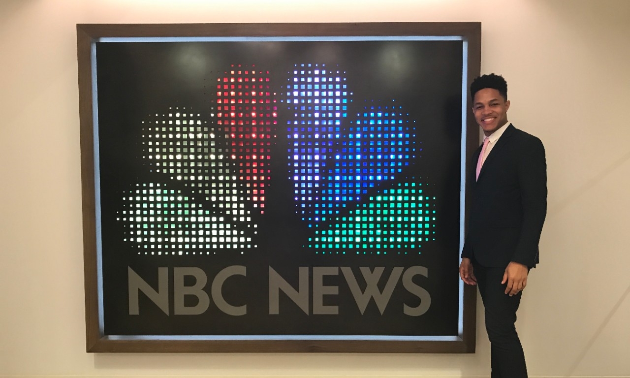 Aberto Jones poses beside an NBC News logo