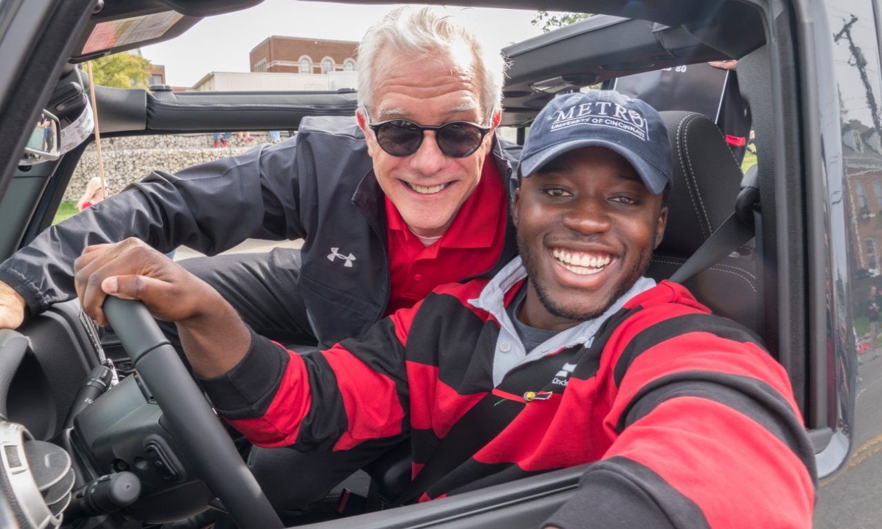 Peter Landgren poses with a UC student in a car during Homecoming