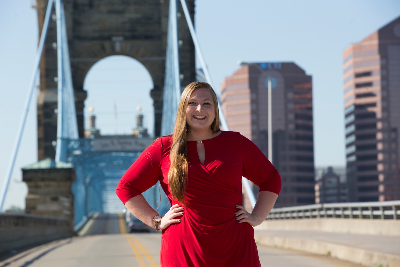 Brianna Karelin stands in front of the suspension bridge in Cincinnati