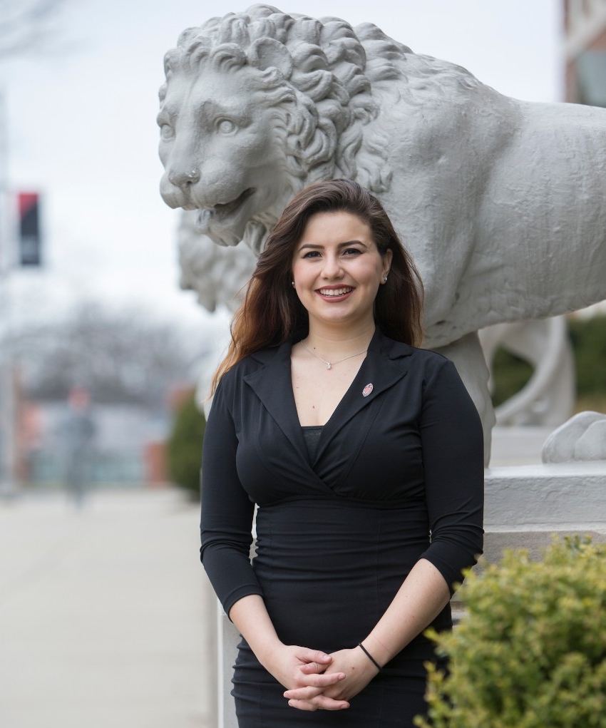 Laura Mendez Ortiz stands near Mick and Mack lions on UC's campus