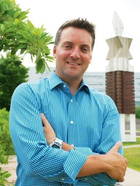 Alumnus Rob Thornton stands in front of a sculpture on the UC campus.