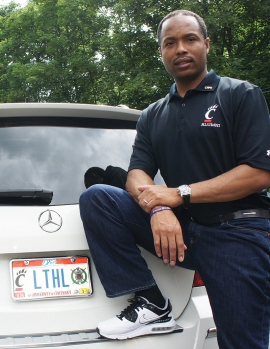 University of Cincinnati alum Lamar Cole, in a Bearcat T-shirt, stands next to his luxury car sporting a Cincinnati Bearcats license plate.