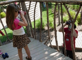 A little girl looks at her father through binoculars.