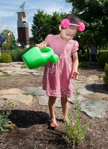 A child pours water from a bucket at UC's PlayScape.