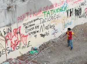 A young bpu reads graffitti on a large imposing wall in Turkey.