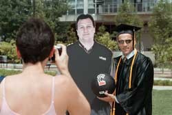 A new grad mugs with a cardboard Bob Huggins at "Snaps and Gowns" following commencement. photo/LisaVentre