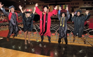 UC President Santa Ono and four recent graduates jump for joy  on the gymnasium court.