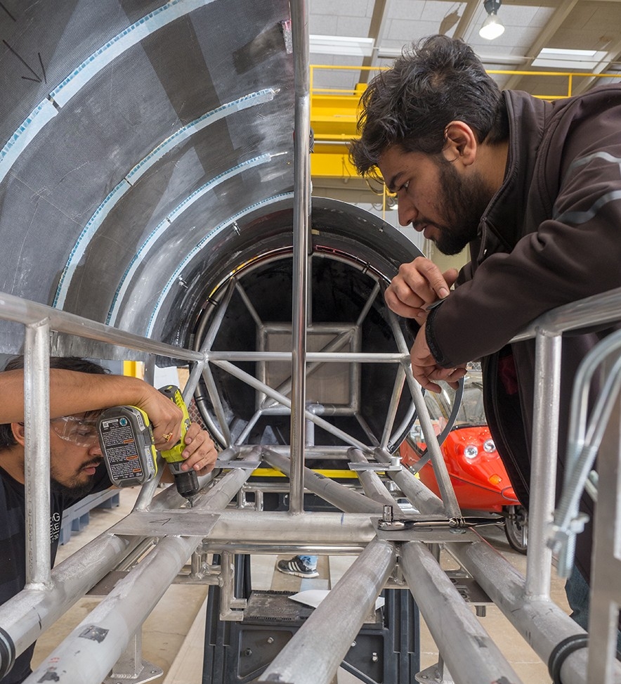 Hyperloop UC team gathers with pod in the Rhodes Hall High Bay at UC.