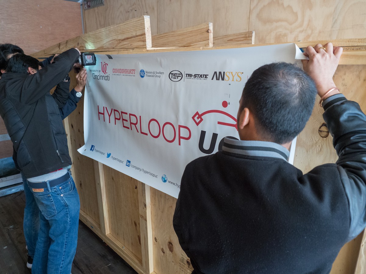 UC students attache the UC Hyperloop banner to the side of the shipping crate.