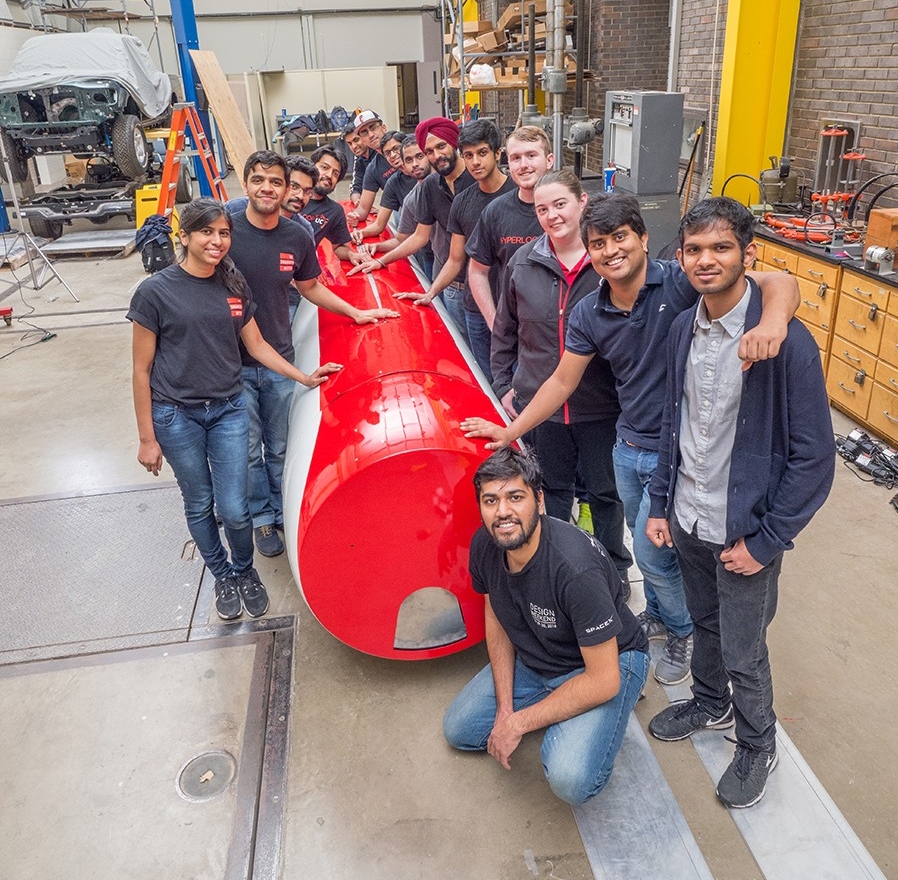 Hyperloop UC team gathers with pod in the Rhodes Hall High Bay at UC.